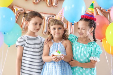 Doğum günü kutlaması. Keki olan çocuklar ve bej arka planda farklı şenlik dekorları.