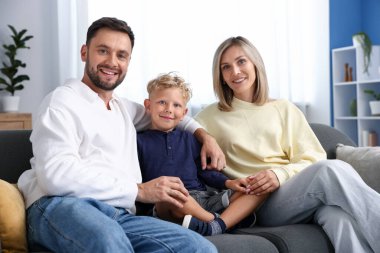 Mutlu bir aile evdeki kanepede oturuyor.