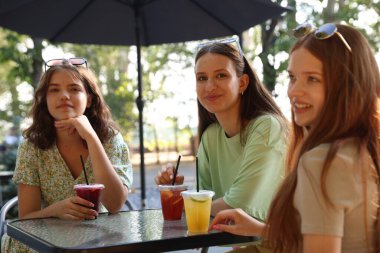 Arkadaşlar açık kafede içeceklerin tadını çıkarıyorlar.