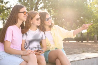 Dışarıda bankta güneş gözlüklü mutlu arkadaşlar.