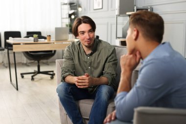 Ofisteki koltuklarda sohbet eden meslektaşlar.