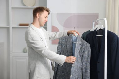 Hazırlanıyor. Genç adam evde kıyafet seçiyor.