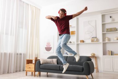 Evde müzik dinlerken zıplayan mutlu bir adam.