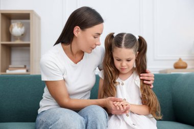 Anne, üzgün kızını evdeki kanepede destekliyor.