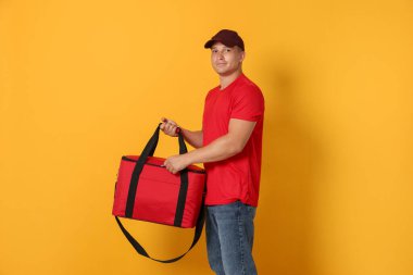 Turuncu arka planda termo çantalı bir kurye. Yemek dağıtım servisi.