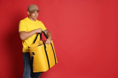 Kırmızı arka planda termo çantalı kurye, mesaj için boşluk. Yemek dağıtım servisi.