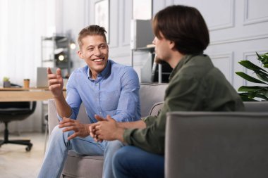 Ofisteki koltuklarda sohbet eden meslektaşlar.