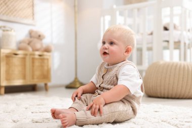 Işık odasında halının üzerinde oturan tatlı bebek.