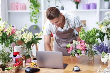 Dükkandaki ahşap masada çalışan bir buket çiçekli profesyonel çiçekçi.