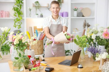 Dükkandaki ahşap masada çalışan bir buket çiçekli profesyonel çiçekçi.