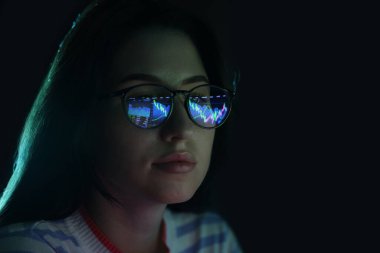 Siyah arka planda yansıması olan gözlüklü genç bir kadın, yakın plan.