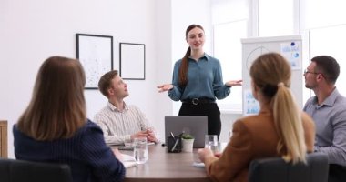 İş koçu ofisteki bir grup insana sunum yapıyor.