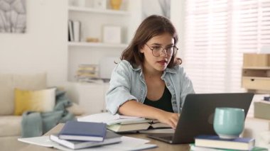 Öğrenci iyi bir sınav geçirdiği için mutlu. Masada dizüstü bilgisayarla sonuçlanıyor.