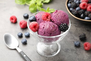 Taze böğürtlenli lezzetli şerbet ve tatlı kasesinde nane şekeri. Gri desenli masa, yakın plan.