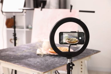 Stüdyoda akıllı telefonlu lezzetli turta ve süt çekmek, seçici odaklanma. Profesyonel yemek fotoğrafçılığı.