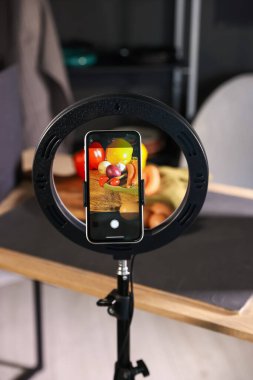 Stüdyoda akıllı telefonla sebze çekmek, ekrana odaklanmak. Profesyonel yemek fotoğrafçılığı.