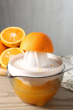 Meyve suyu. Meyve sıkacağı ve taze portakallar ahşap masada, yakın plan.