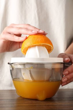 Meyve suyu. Tahta masada portakallı kadın meyve sıkacağı kullanıyor, yakın plan.