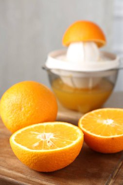 Meyve suyu. Taze portakallar ve meyve sıkacağı masada, yakın plan.