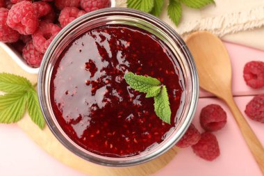 Tatlı ahududu reçeli cam kavanozda, böğürtlen ve nane şekeri pembe ahşap masada, düz yerde