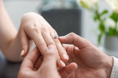 Evlenme teklif ediyorum. Adam içeride kız arkadaşının parmağına nişan yüzüğü takıyor.