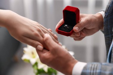 Nişan yüzüklü bir adam içeride kız arkadaşına evlenme teklif ediyor.