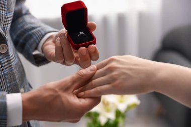 Nişan yüzüklü bir adam içeride kız arkadaşına evlenme teklif ediyor.