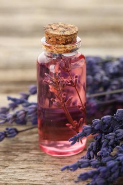 Lavanta yağı şişede ve çiçekler ahşap masada, yakın plan.
