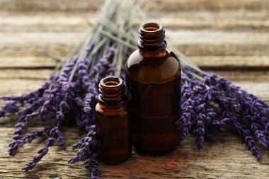 Lavanta yağı şişelerde, çiçekler ahşap masada, yakın plan