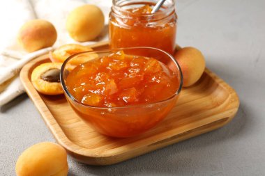 Lezzetli kayısı reçeli ve açık gri masada taze meyveler. Yakın plan.