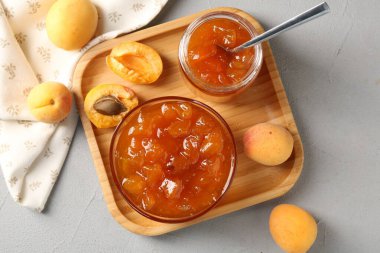 Lezzetli kayısı reçeli ve açık gri masada taze meyveler.