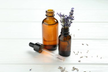 Lavanta yağı ve çiçekler beyaz ahşap masada, yakın plan.