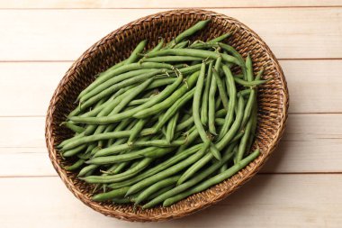 Hasır sepetin içinde taze bezelye kabukları açık ahşap masa, üst manzara
