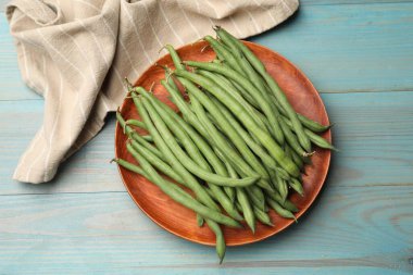 Mavi ahşap masada bir sürü çiğ yeşil fasulye var.