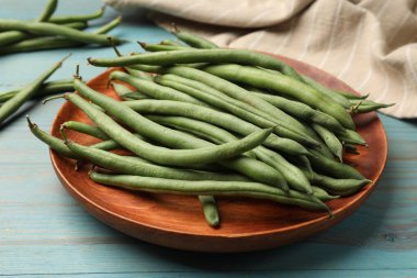 Mavi ahşap masada bir sürü çiğ yeşil fasulye, yakın plan.