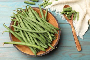 Mavi ahşap masada bir sürü çiğ yeşil fasulye vardı.