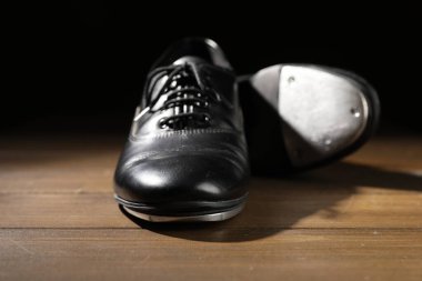 Ahşap zeminde siyah arka planda bir çift ayak izi, yakın plan. Step dansı.