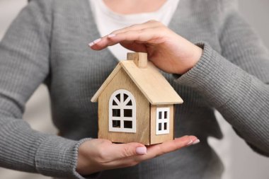 Ev güvenliği. Işıklı arka planda ev modeli olan kadın, yakın plan