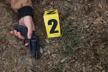 Adli tıp uzmanlığı. Cesedin bulunduğu suç mahalli, silah ve işaret açık havada, üst tarafta.