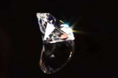 Ayna yüzeyinde parlak bir elmas, siyah arka plana karşı, yakın plan.