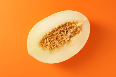 Turuncu arka planda olgun kavunun yarısı, üst manzara.