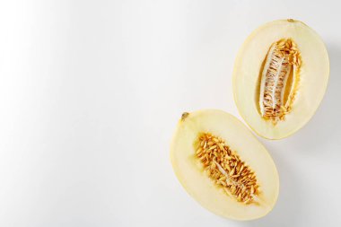 Beyaz arka planda olgun kavun yarımları, düz uzanmış. Metin için boşluk