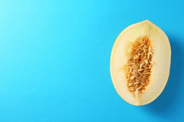 Açık mavi arka planda olgun kavunun yarısı, üst manzara. Metin için boşluk