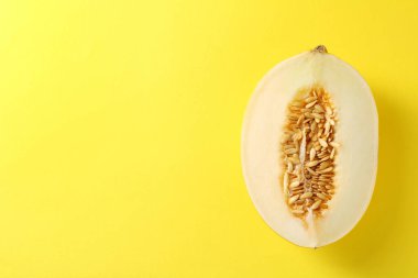 Sarı arka planda olgun kavunun yarısı, üst manzara. Metin için boşluk