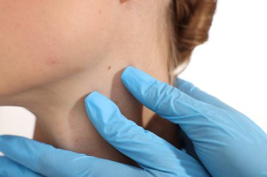 Doktor beyaz arka planda genç kadının benini inceliyor, yakın plan.