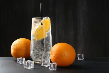 Siyah ahşap masada portakal dilimleri ve buz küpleriyle soda tazeliyorum. Metin için boşluk