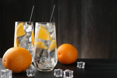 Portakal dilimleri ve siyah ahşap masadaki buz küpleriyle soda tazeleniyor. Yakın plan. Metin için boşluk