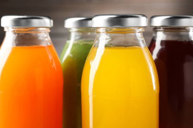 Cam şişelerdeki lezzetli sıvılar, bulanık kahverengi arka plan, yakın plan.