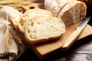 Taze ekmek, bıçak ve buğday çivileri ahşap masada, yakın plan.