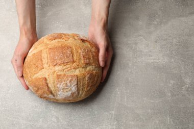 Gri masada bir somun taze ekmeği olan kadın, üst manzara. Metin için boşluk